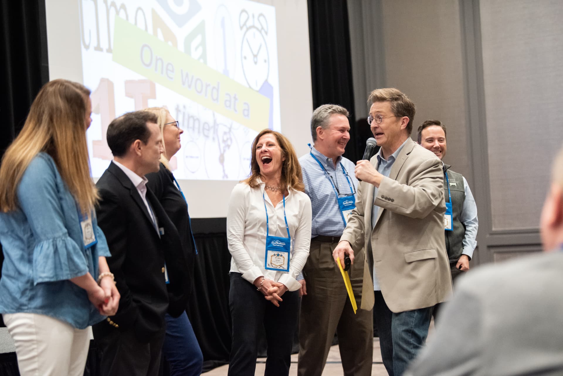 Tim Clue on stage with volunteers laughing during an interactive bit